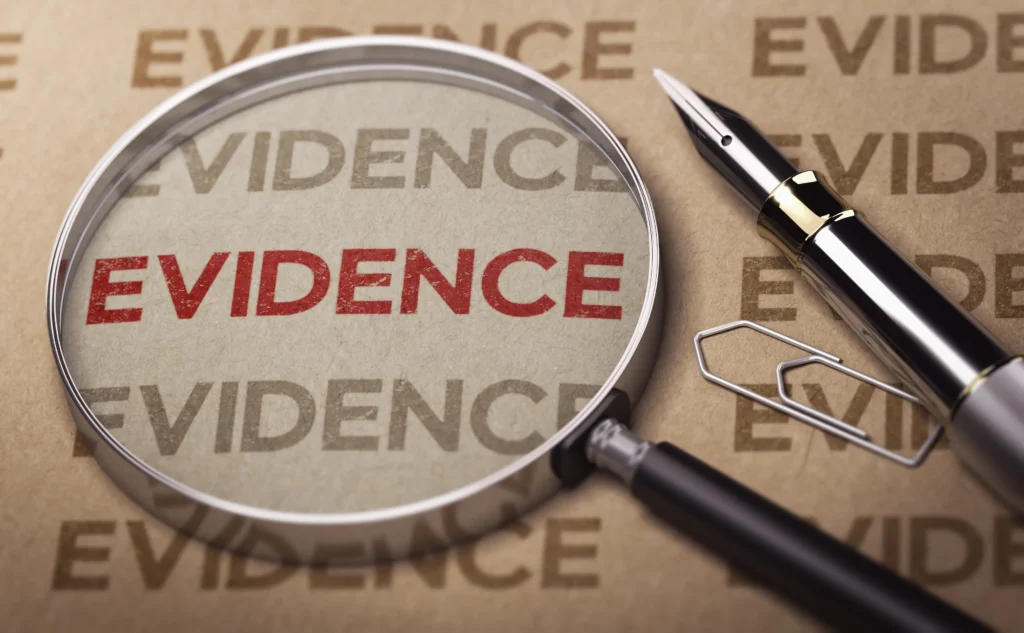 A large magnifying glass, pen and a paper with the word 'evidence' written in red.