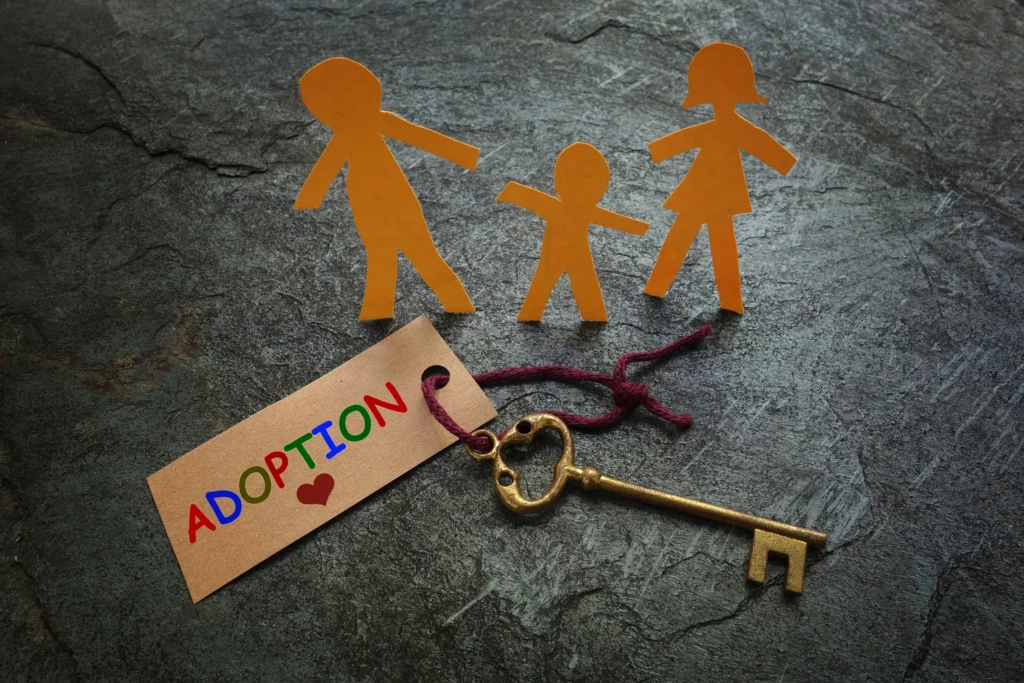 Paper cutouts of a family with a key and a tag that reads "ADOPTION".